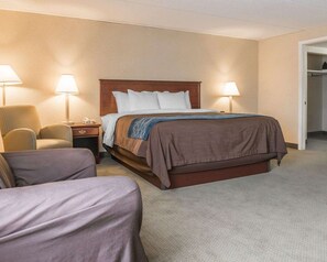 A hotel room with a bed, two bedside lamps, a chair, and a nightstand.