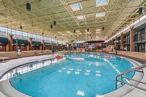 Ein Hallenbad mit hoher Decke, großen Glaswänden und einer Ziegelaußenwand.