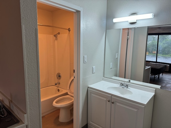 Bathroom features a white bathtub, toilet, and sink with a mirror.