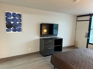 Relax in a stylish room with a flat-screen TV, abstract art, and a comfortable bed.