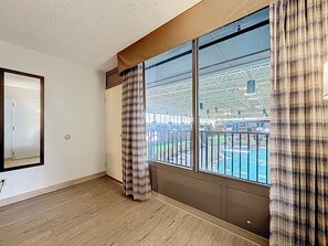 A room with a large window, a view of an outdoor pool, and a door.