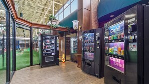 A modern indoor area with vending machines, a glass door entrance, and a view of an outdoor space.
