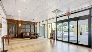 Un hall d’entrée spacieux avec un comptoir d’accueil, un canapé en cuir et une porte en verre donnant sur l’extérieur.