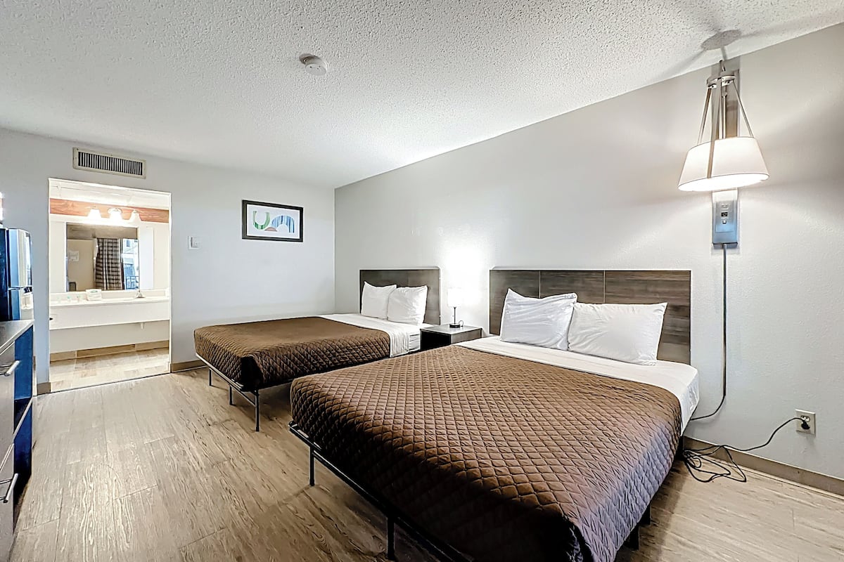 Een hotelkamer met twee bedden, een badkamer met een spiegel en een kitchenette.