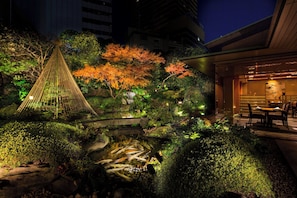 A nighttime garden with a water feature, a hammock, and a dining area. - InterContinental ANA Tokyo by IHG (Tokyo)