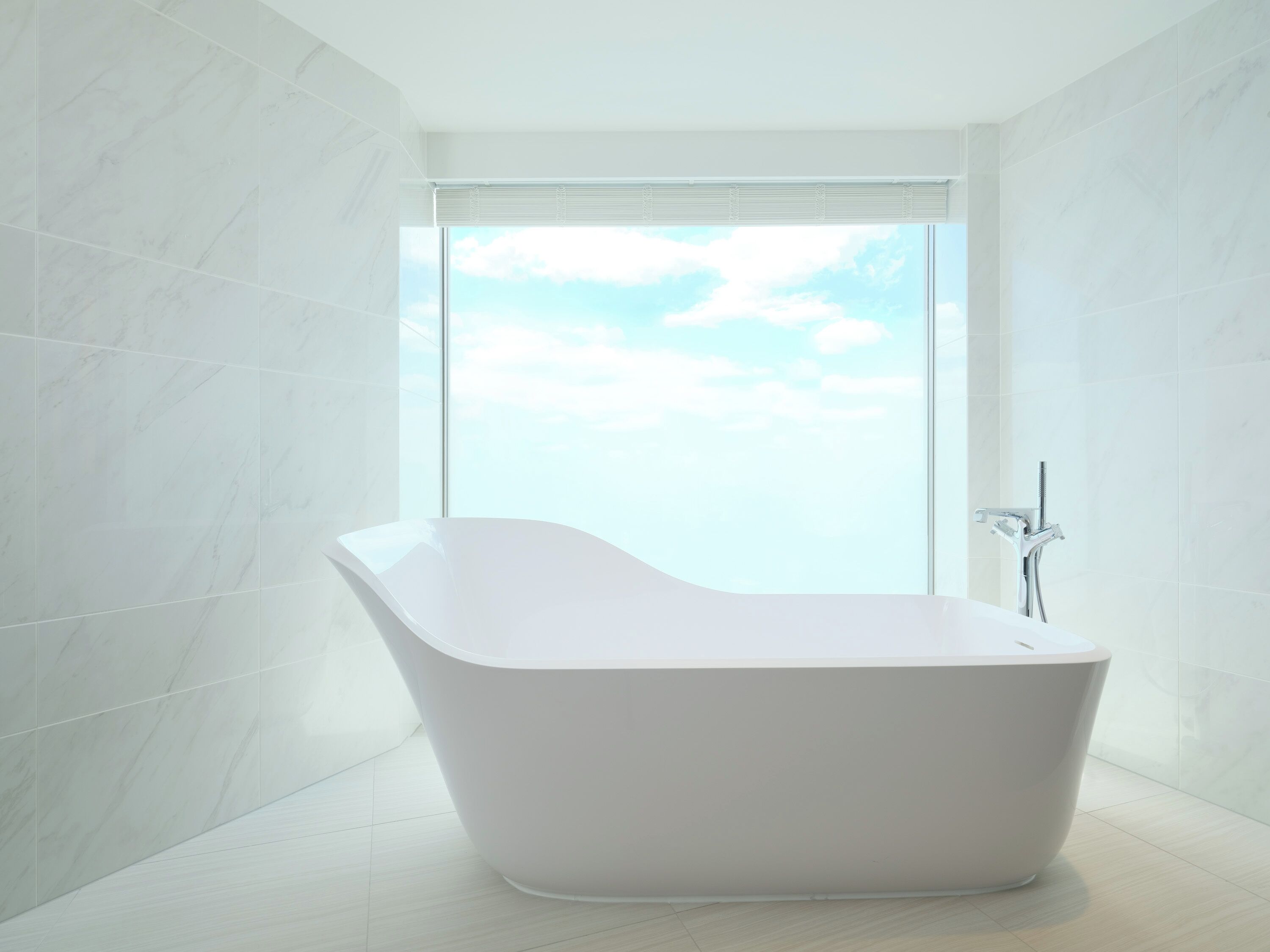A modern bathroom with a freestanding bathtub, large window, and white marble walls.