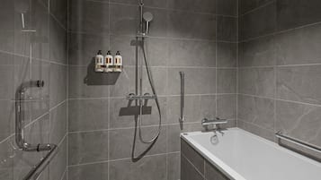 A modern bathroom with a bathtub, shower, and handrails.