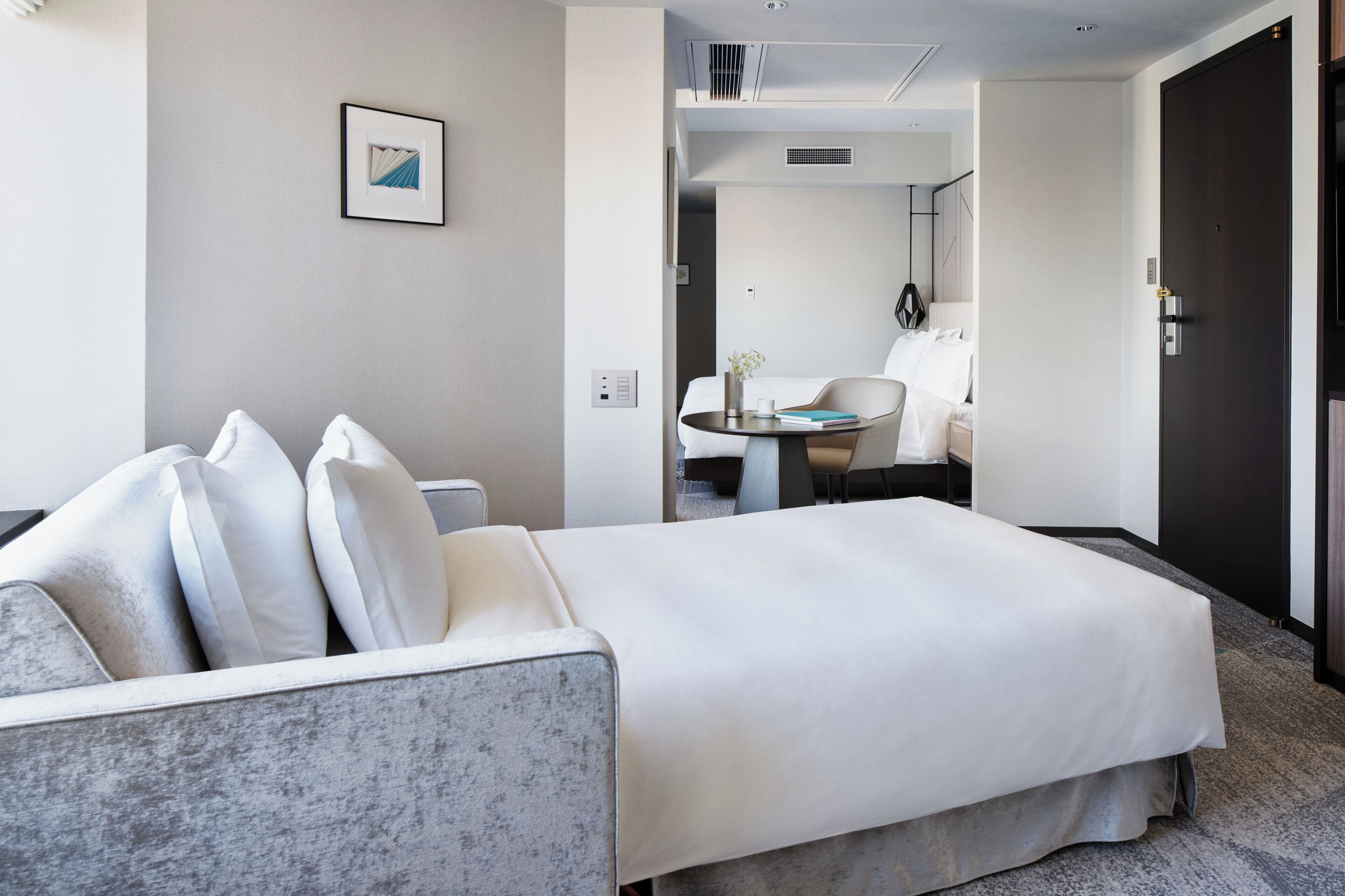 Une chambre d’hôtel comprenant un lit, un coin salon avec une table et une porte.