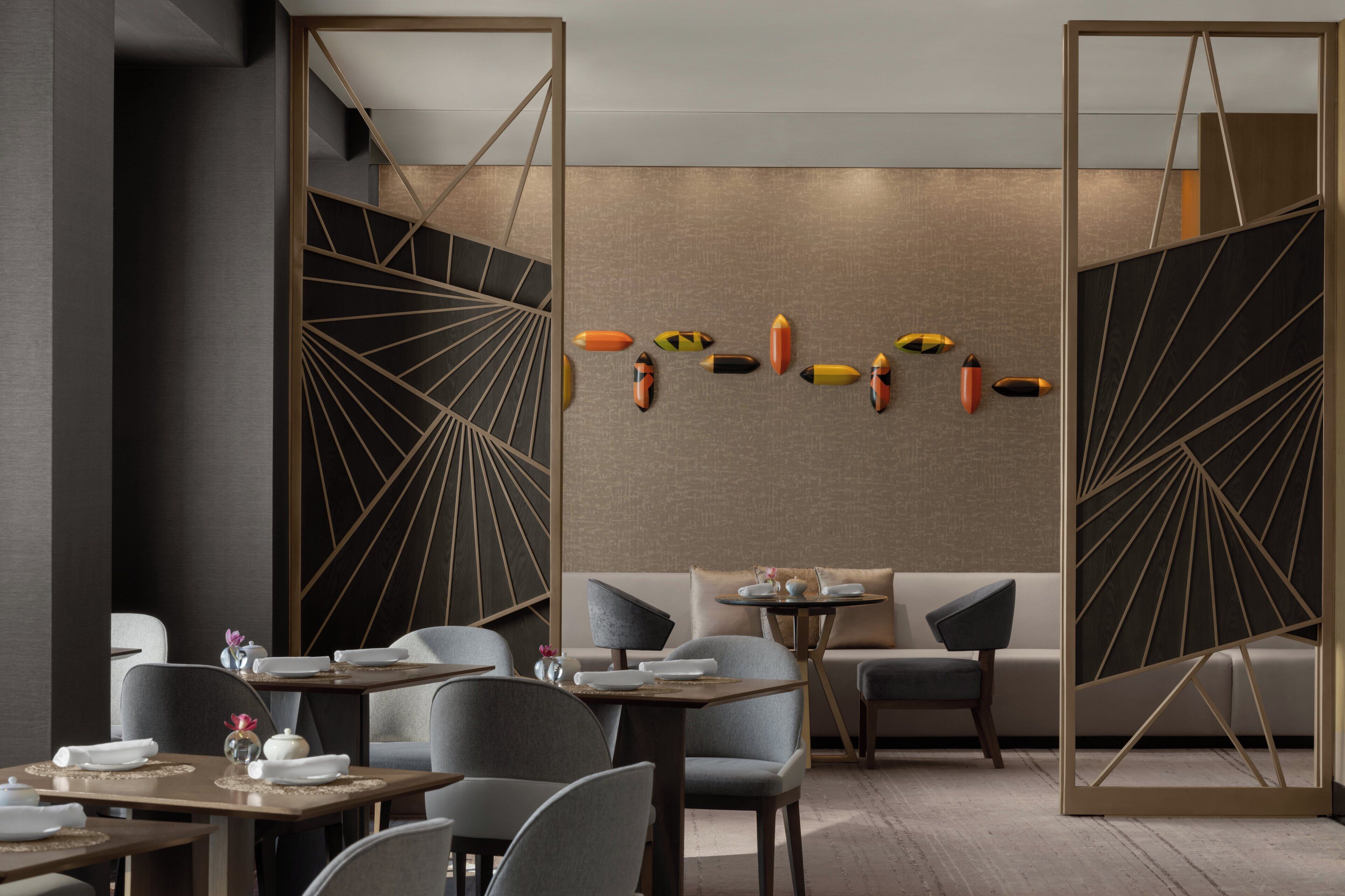 Un'area pranzo moderna con un design geometrico a parete, un divano e un tavolo apparecchiato per consumare i pasti.