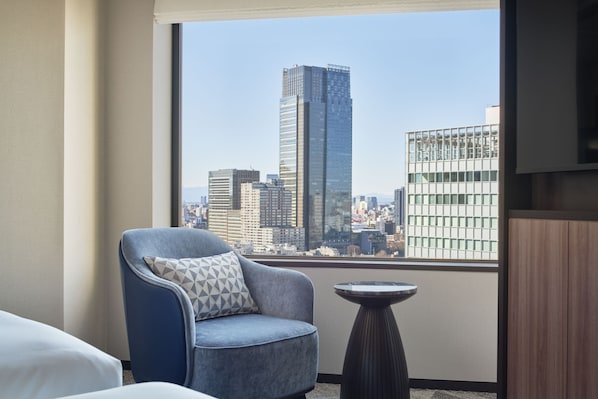 A room with a city view, a blue armchair with a geometric pillow, a small round table, and a wooden cabinet. - InterContinental ANA Tokyo by IHG (Tokyo)