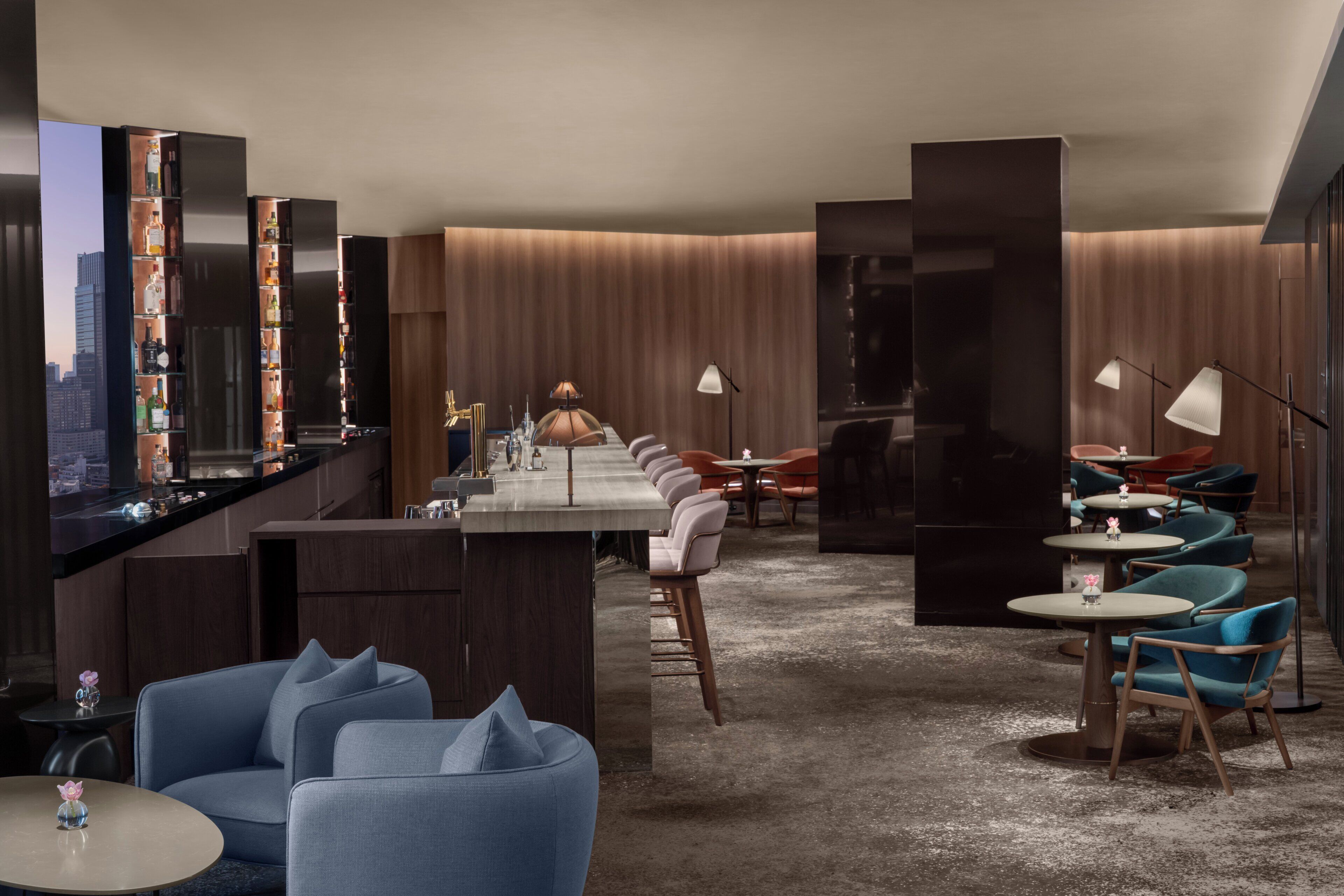 A modern hotel lobby with a bar area, seating arrangements, and a city view.