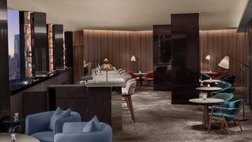 A modern hotel lobby with a bar area, seating arrangements, and a city view.
