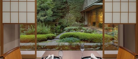 A traditional Japanese-style dining room with tatami mats, a low table, and sliding doors.