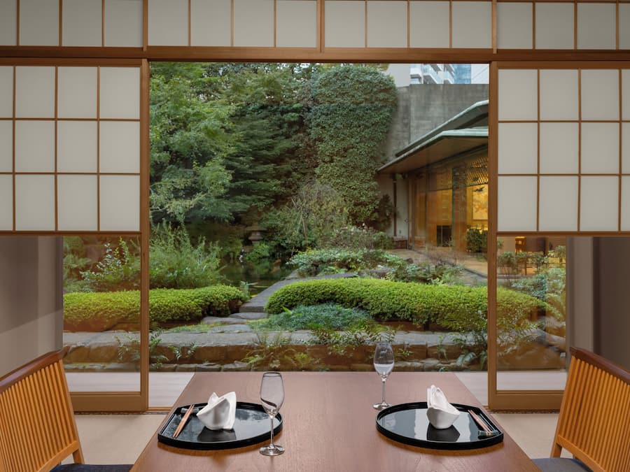 Comedor tradicional japonés con esteras de tatami, una mesa baja y puertas correderas.