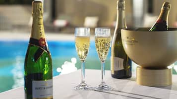 Une table avec deux coupes à champagne, une bouteille de champagne Moët & Chandon et un seau à champagne, le tout placé près d’une piscine.