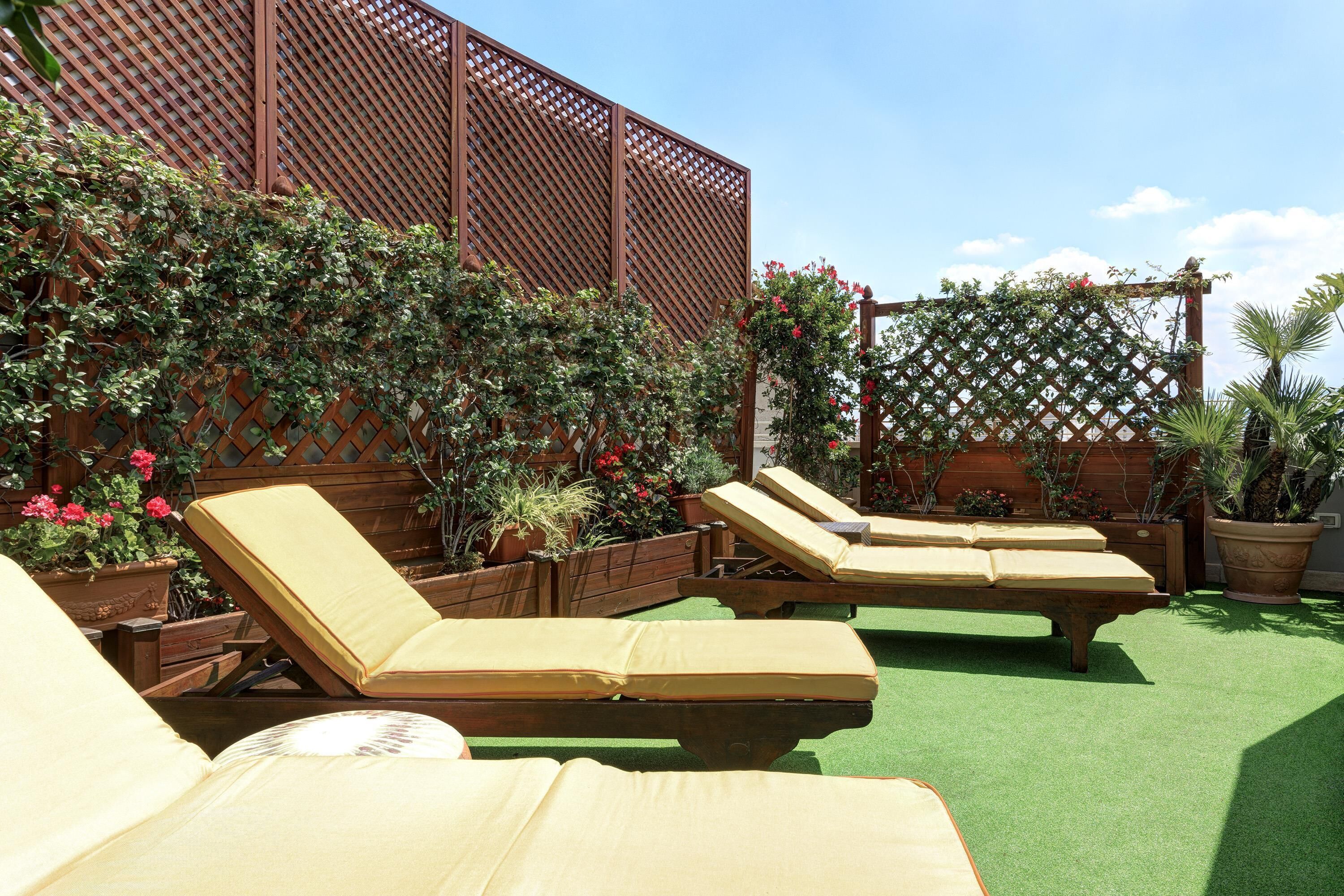A patio area with lounge chairs and a wooden lattice structure.