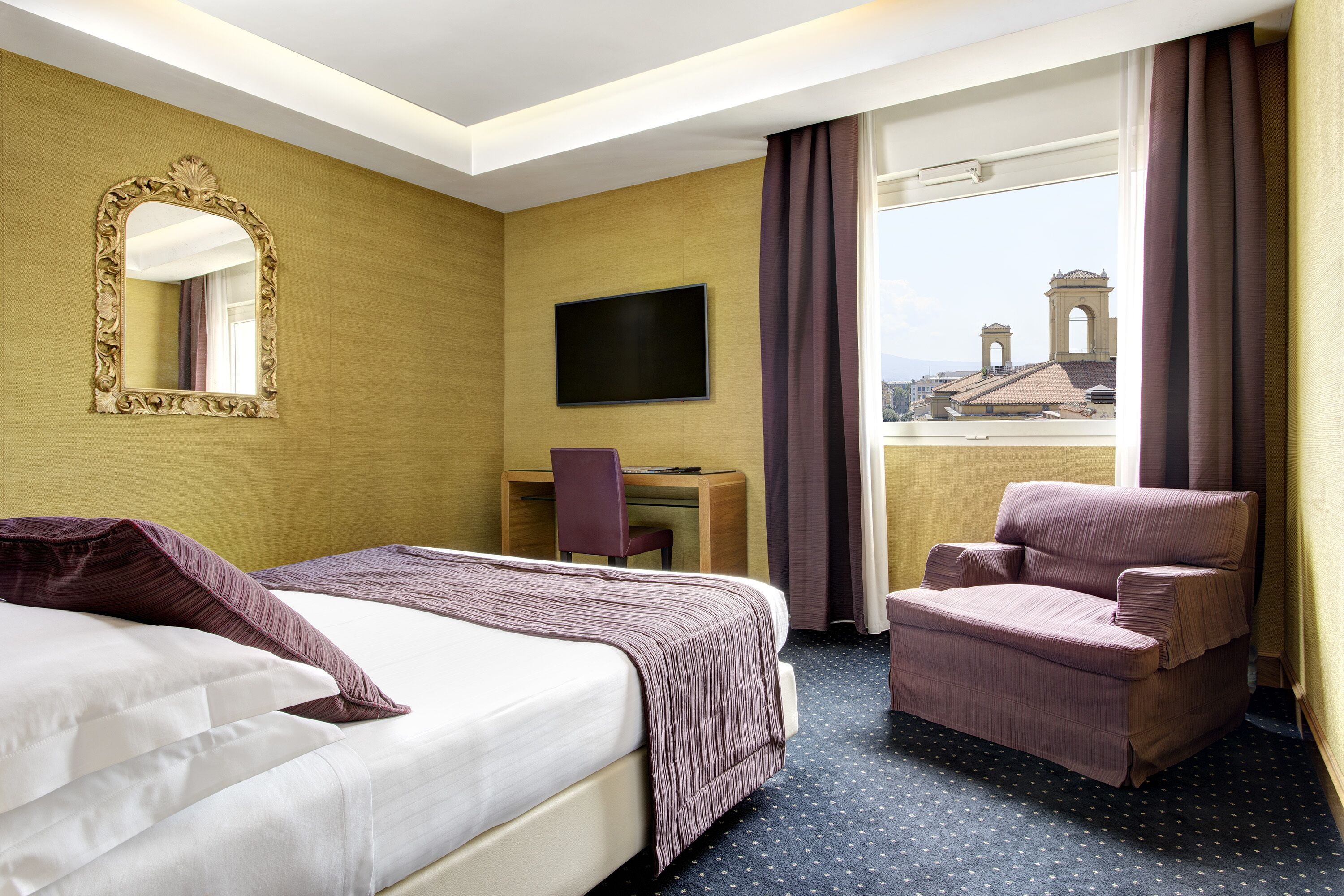 Une chambre d’hôtel comprenant un lit, un bureau avec une chaise, une télévision et une vue sur le paysage urbain.