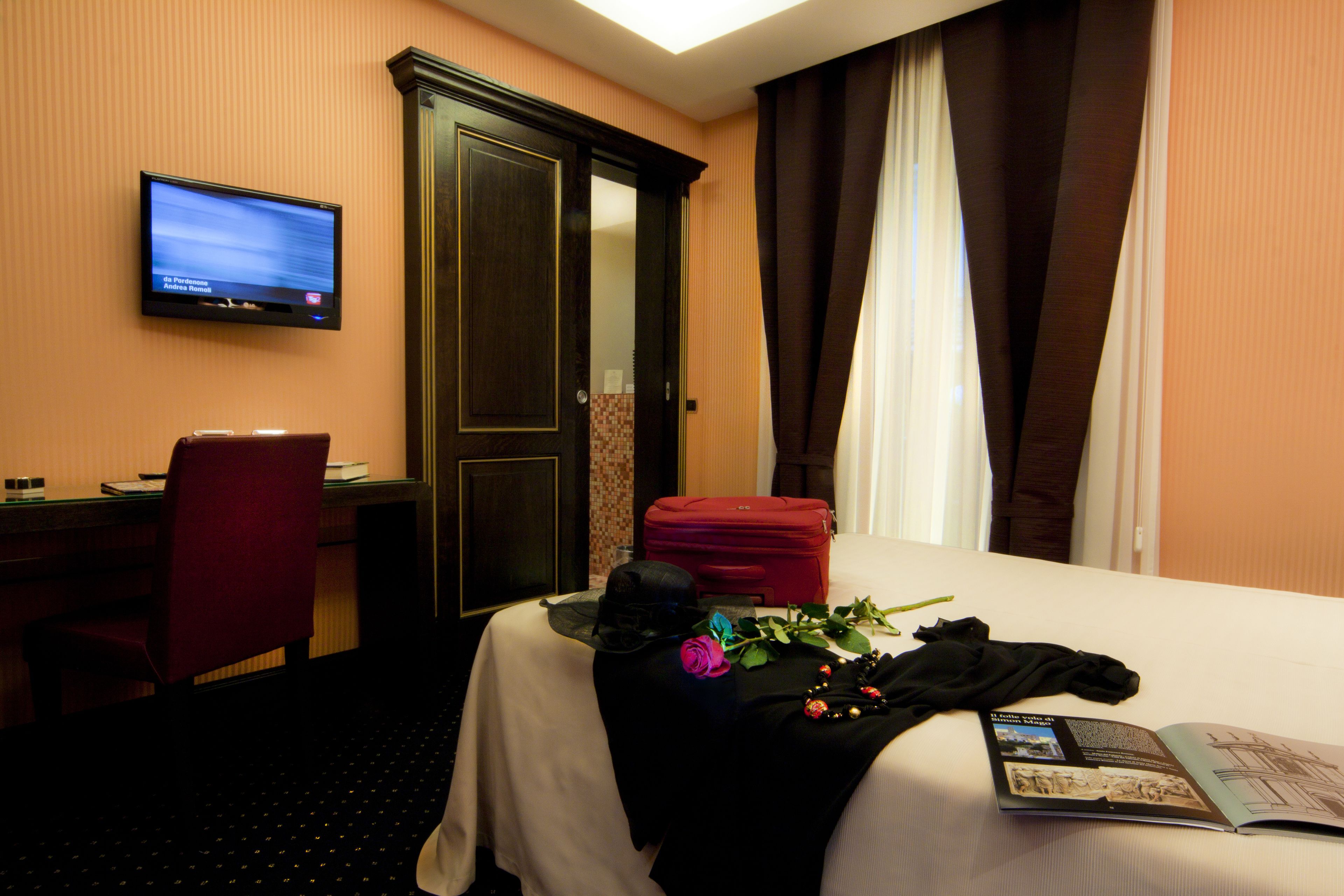 Une chambre d’hôtel avec un lit, un bureau, une chaise, une télévision et une porte.