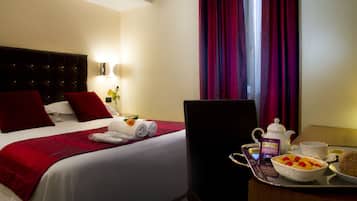 A hotel room with a neatly made bed, a tray with breakfast items, and a window with curtains.