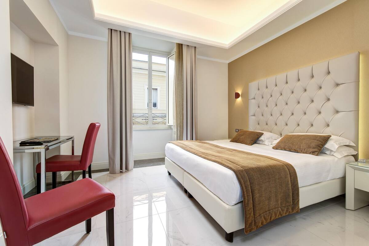 Una camera d'albergo con un letto, una scrivania e una sedia.