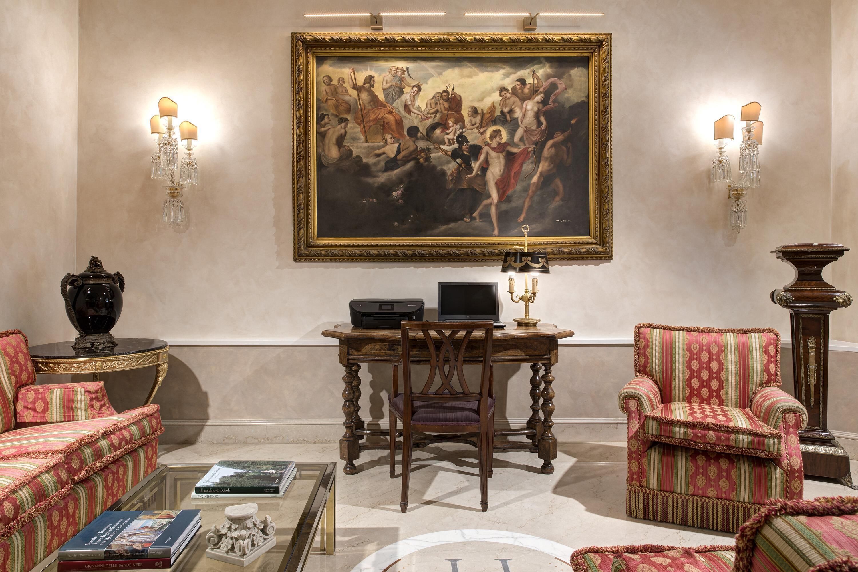 A classic interior with a large classical painting, elegant furniture, and a desk with a computer.