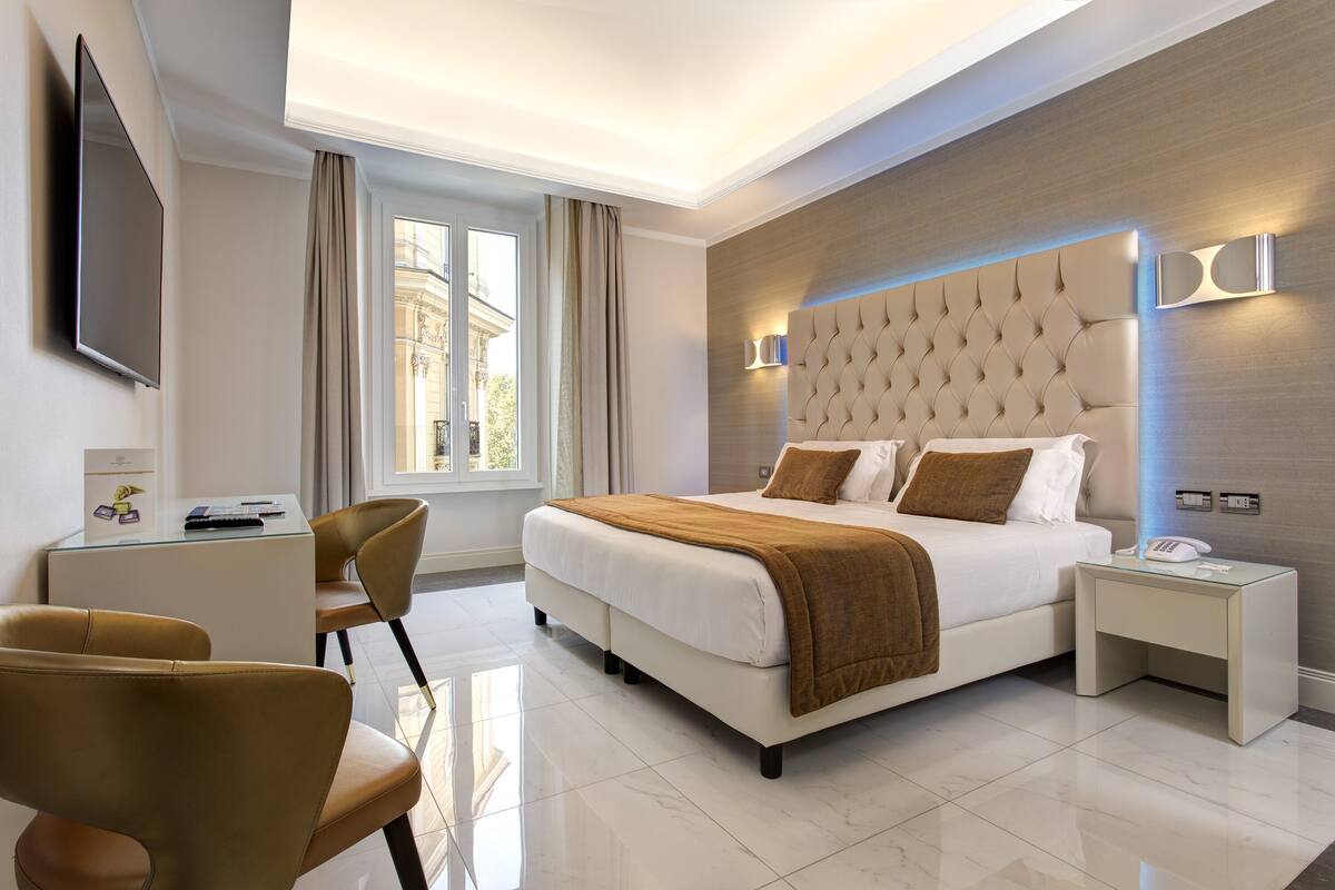 Una camera d'albergo moderna con un letto grande, una scrivania e una sedia.