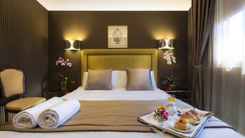 A hotel room with a large bed, two bedside lamps, a chair, a tray with breakfast items, and a vase with flowers.