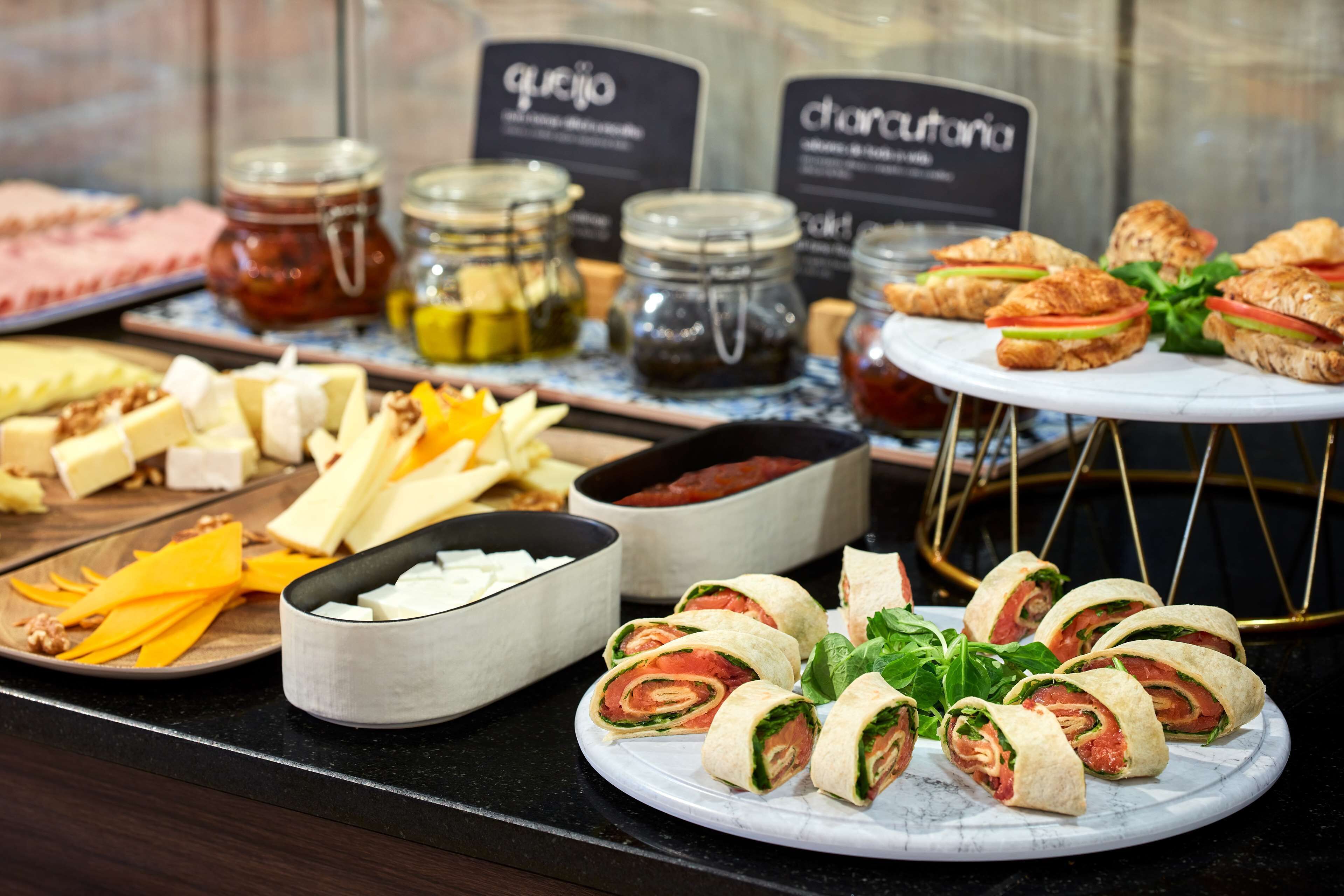 A buffet with various food items including cheese, pastries, and sandwiches.