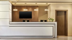 Un comptoir d’accueil moderne doté d’un téléviseur à écran plat, de luminaires suspendus et d’un mur revêtu de panneaux en bois.