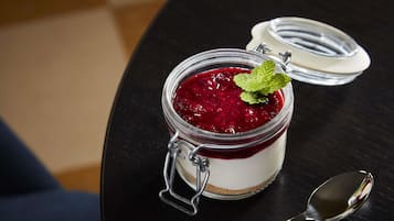 Un postre en un tarro de cristal con tapa de metal, sobre una superficie oscura, con una cuchara al lado.