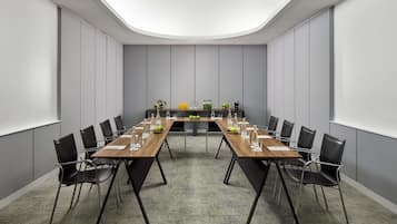 A conference room with a long table, black chairs, and a carpeted floor.