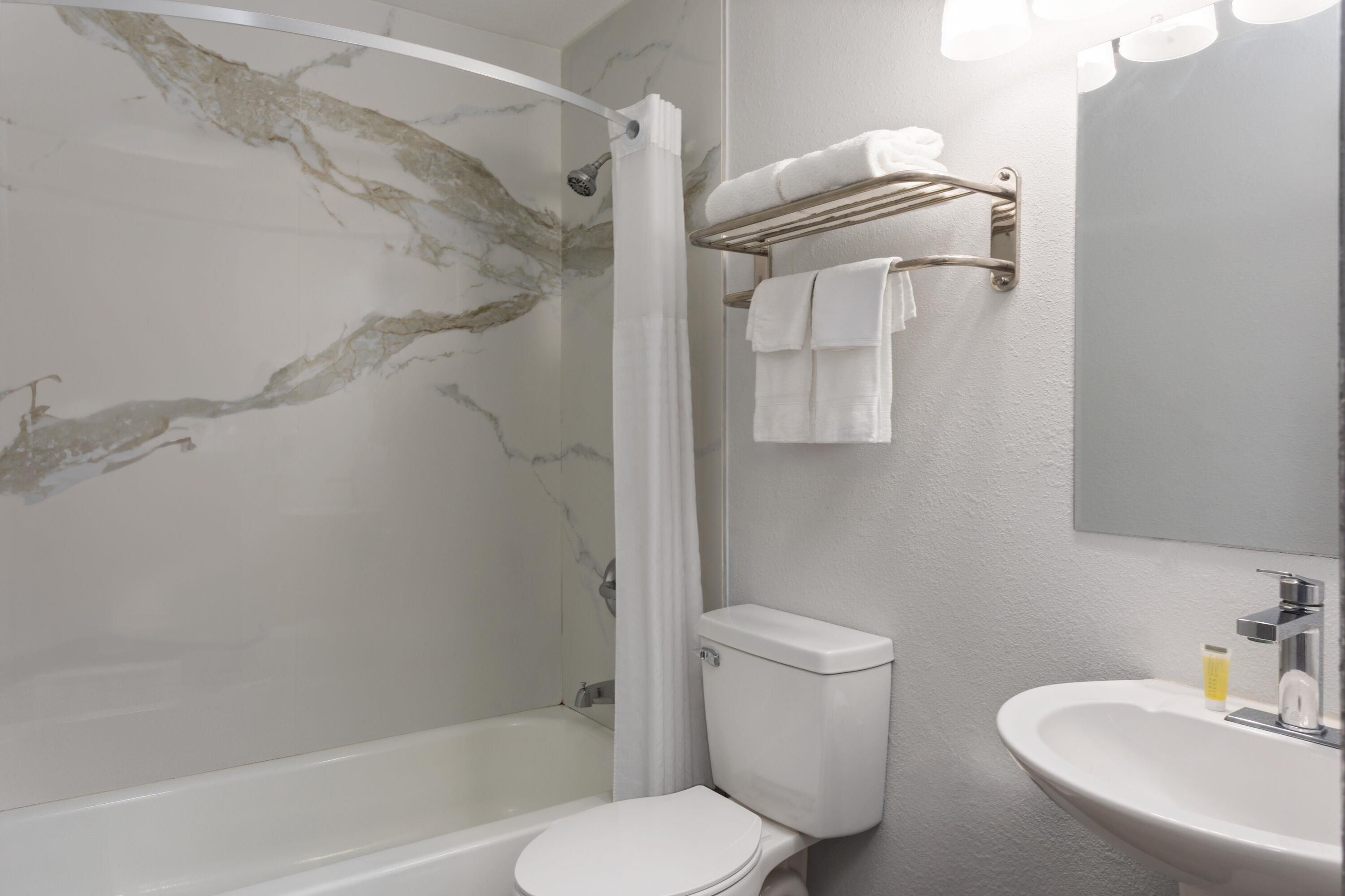 Un baño con ducha, inodoro, lavabo y toallero.