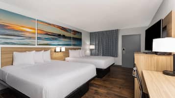 Habitació d'hotel amb dos llits, una taula de treball, una televisió i un quadre amb un paisatge maritim al capvespre.
