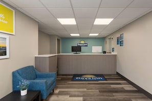 Uma área de recepção com uma cadeira azul, balcão de recepção e o logotipo da Days Inn.