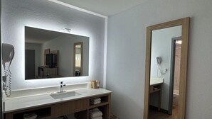 Un baño moderno con un espejo grande, un lavabo y un secador de pelo.