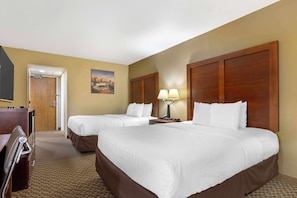 A hotel room with two beds, a desk, a chair, a lamp, and a painting on the wall.