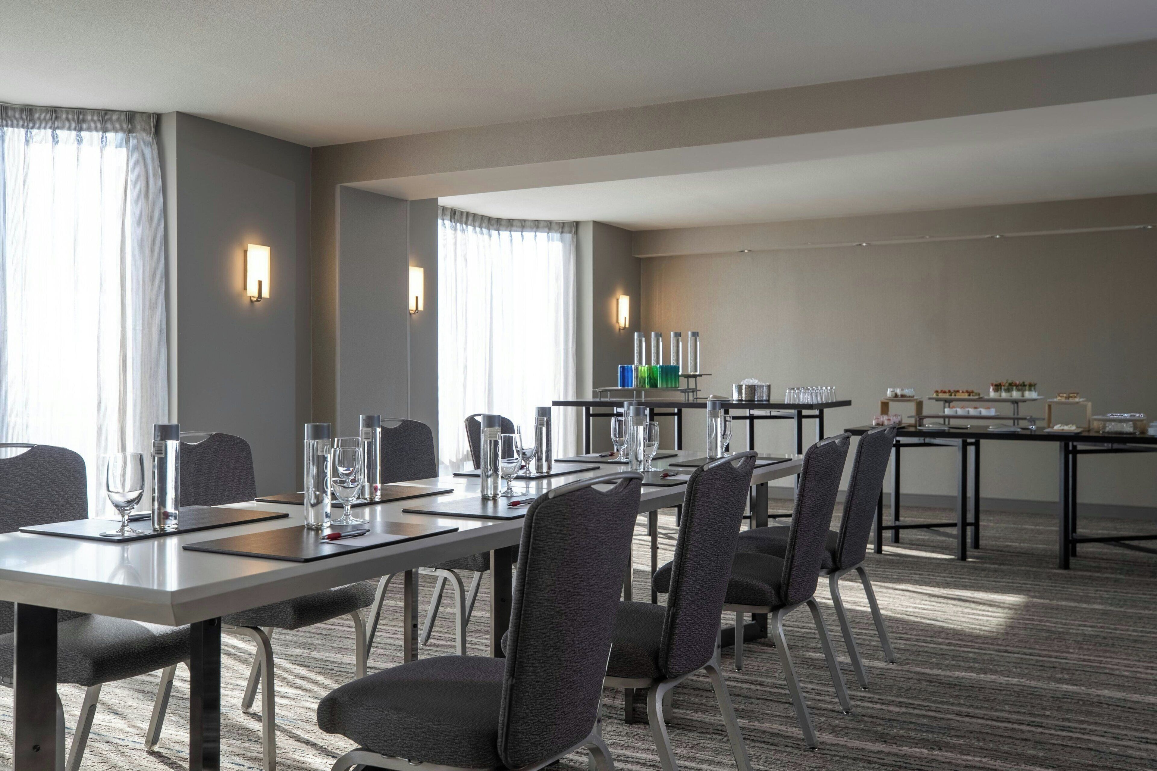 A conference room with a long table, chairs, and a buffet area with food and drinks.