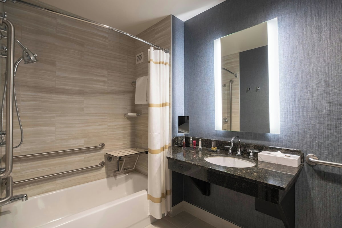 Een moderne badkamer met een badkuip, douche en een wastafelmeubel met een wastafel en spiegel.
