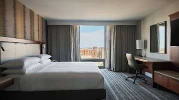 Une chambre d’hôtel avec un grand lit, un bureau, une chaise et un téléviseur.