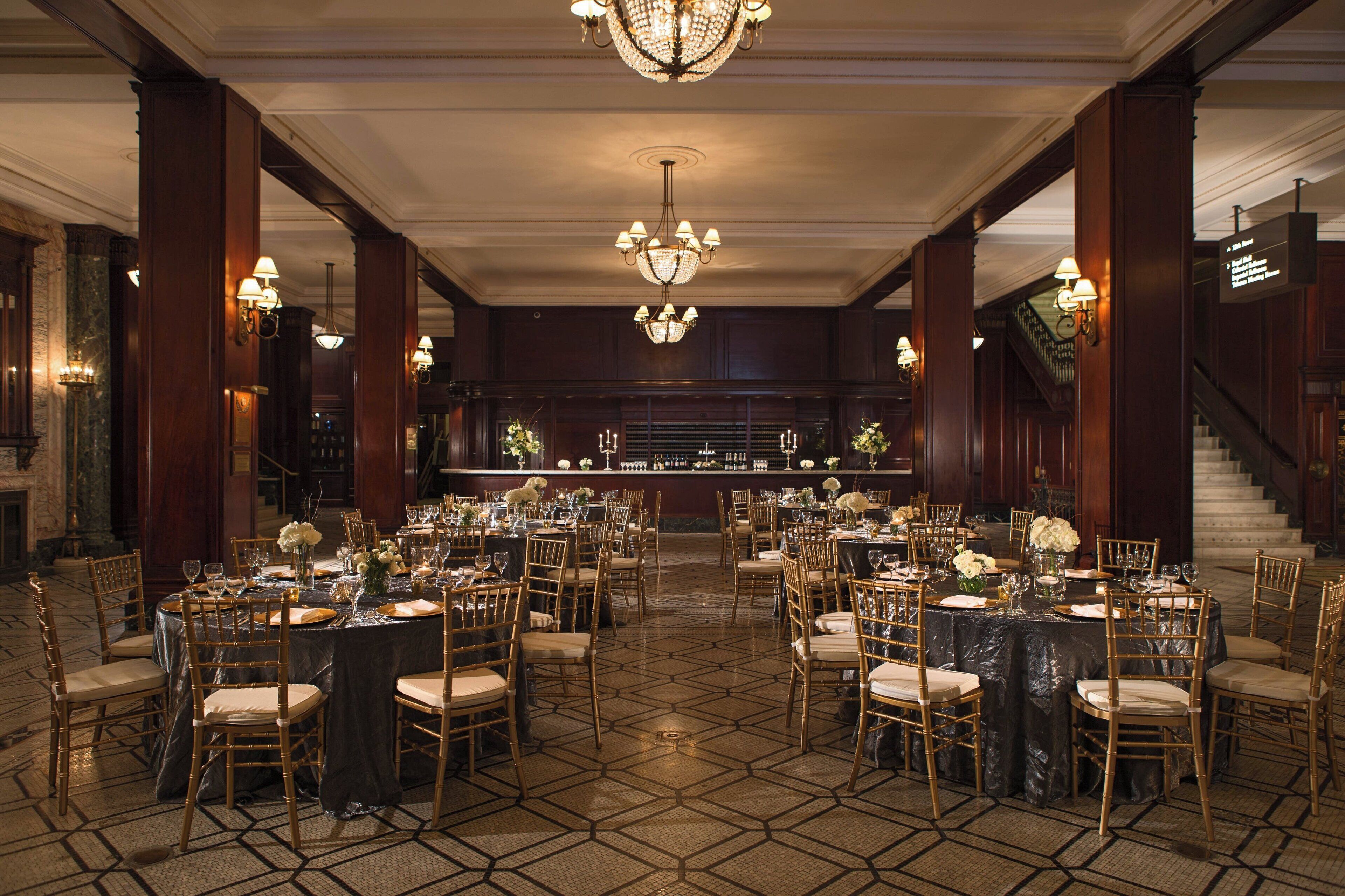 A banquet hall with multiple round tables set for dining, each with chairs and centerpieces.