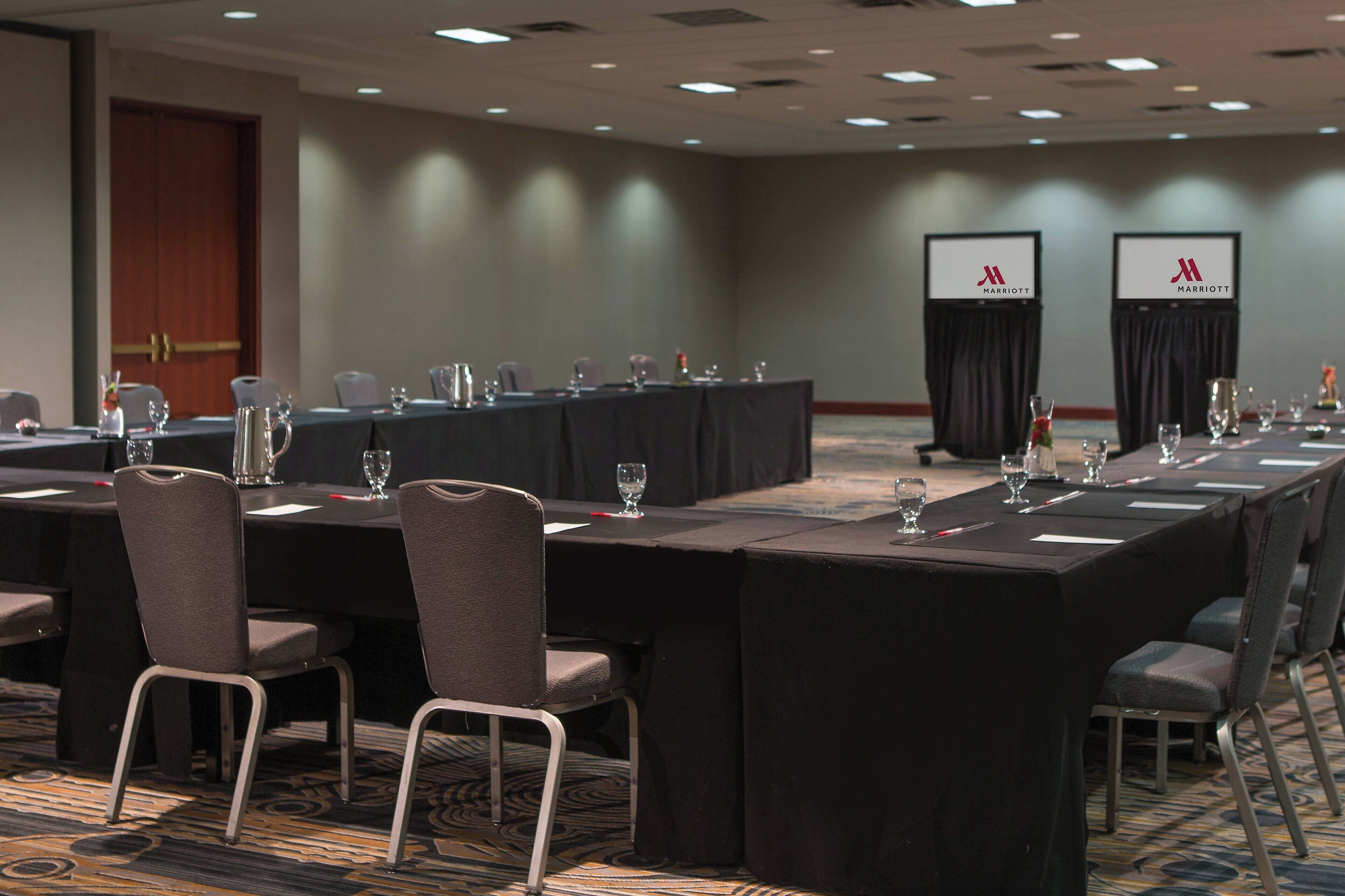 Ett konferensrum med långa bord, stolar och skyltar med Marriott-logotypen.
