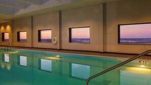 Une piscine intérieure dotée de grandes baies vitrées offrant une vue sur le coucher du soleil.