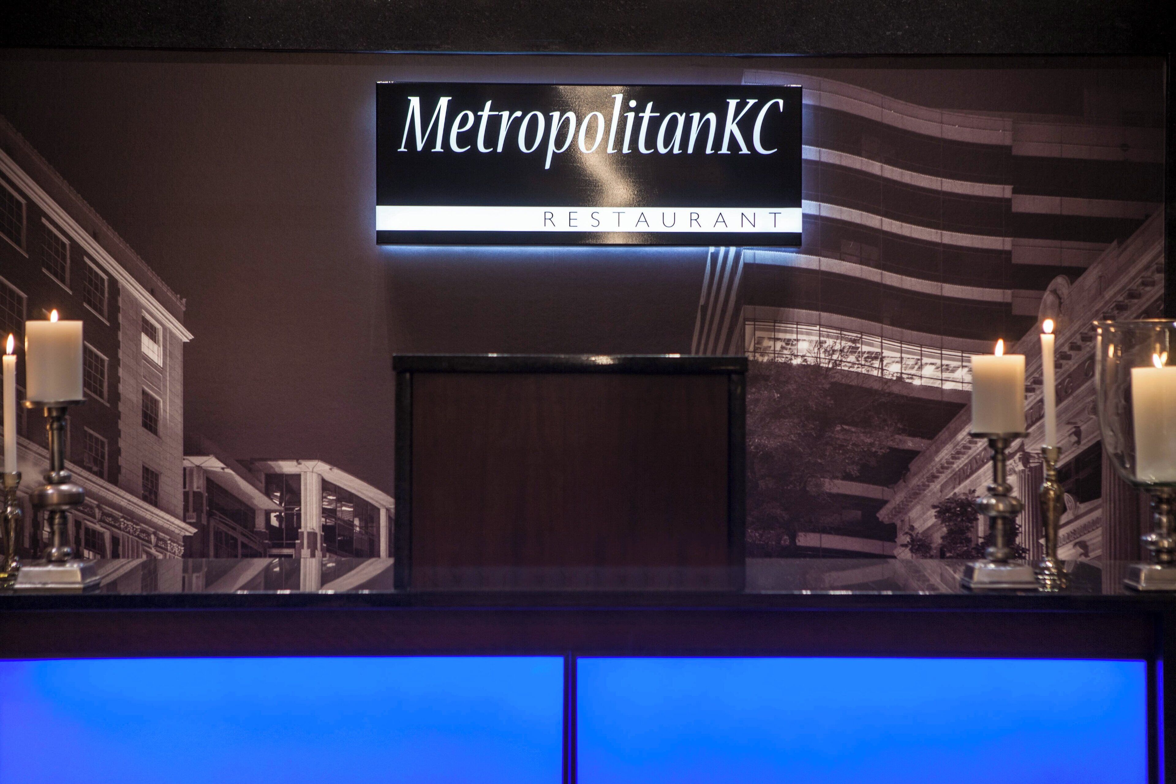 En restaurangskylt med namnet ”MetropolitanKC” och en modern inredning med ett mörkt färgtema och reflekterande ytor.