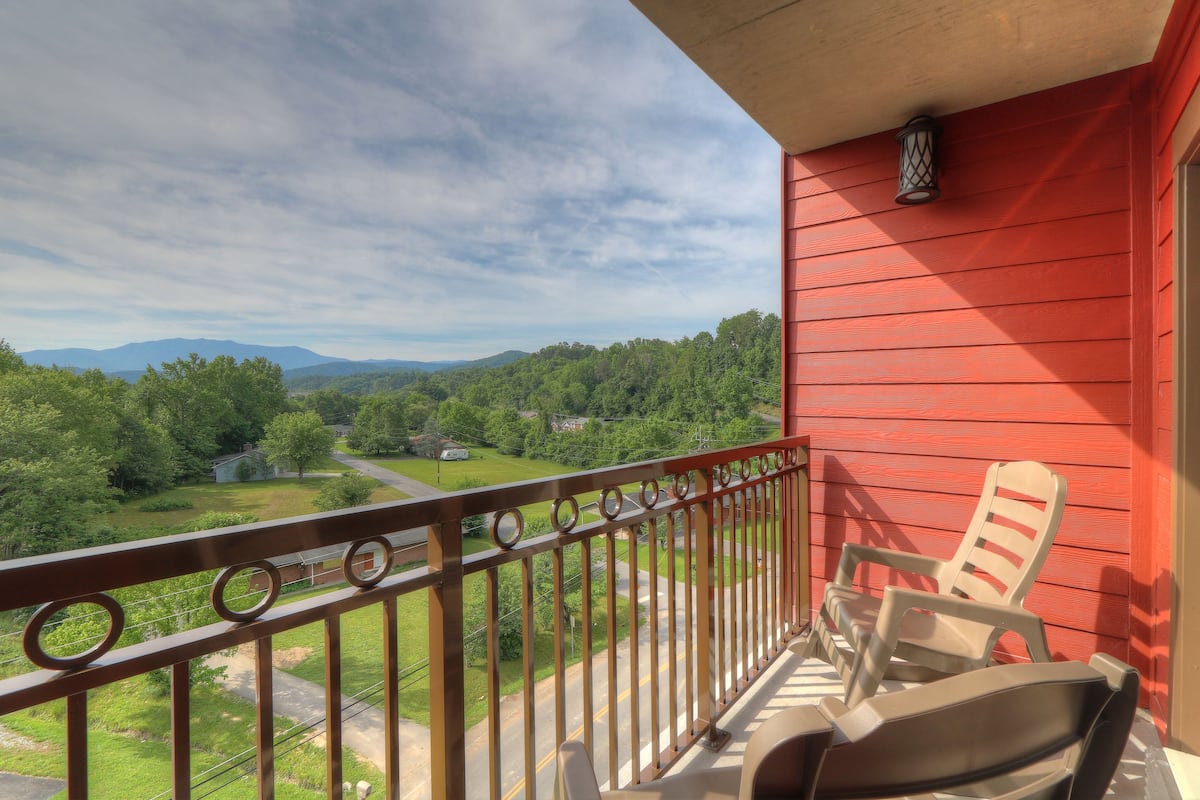 Un balcon donnant sur un paysage verdoyant et des montagnes.