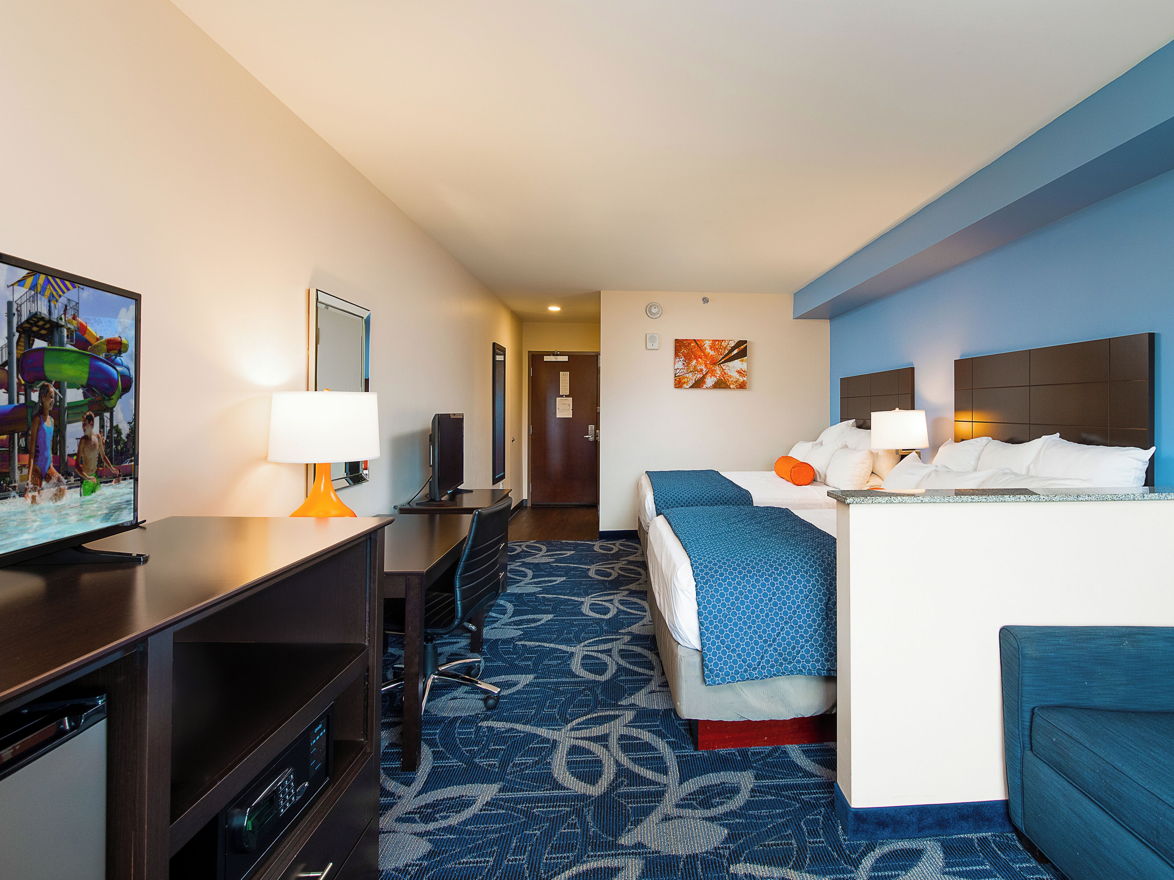 Een hotelkamer met een bed, bureau, stoel, televisie en een badkamer.