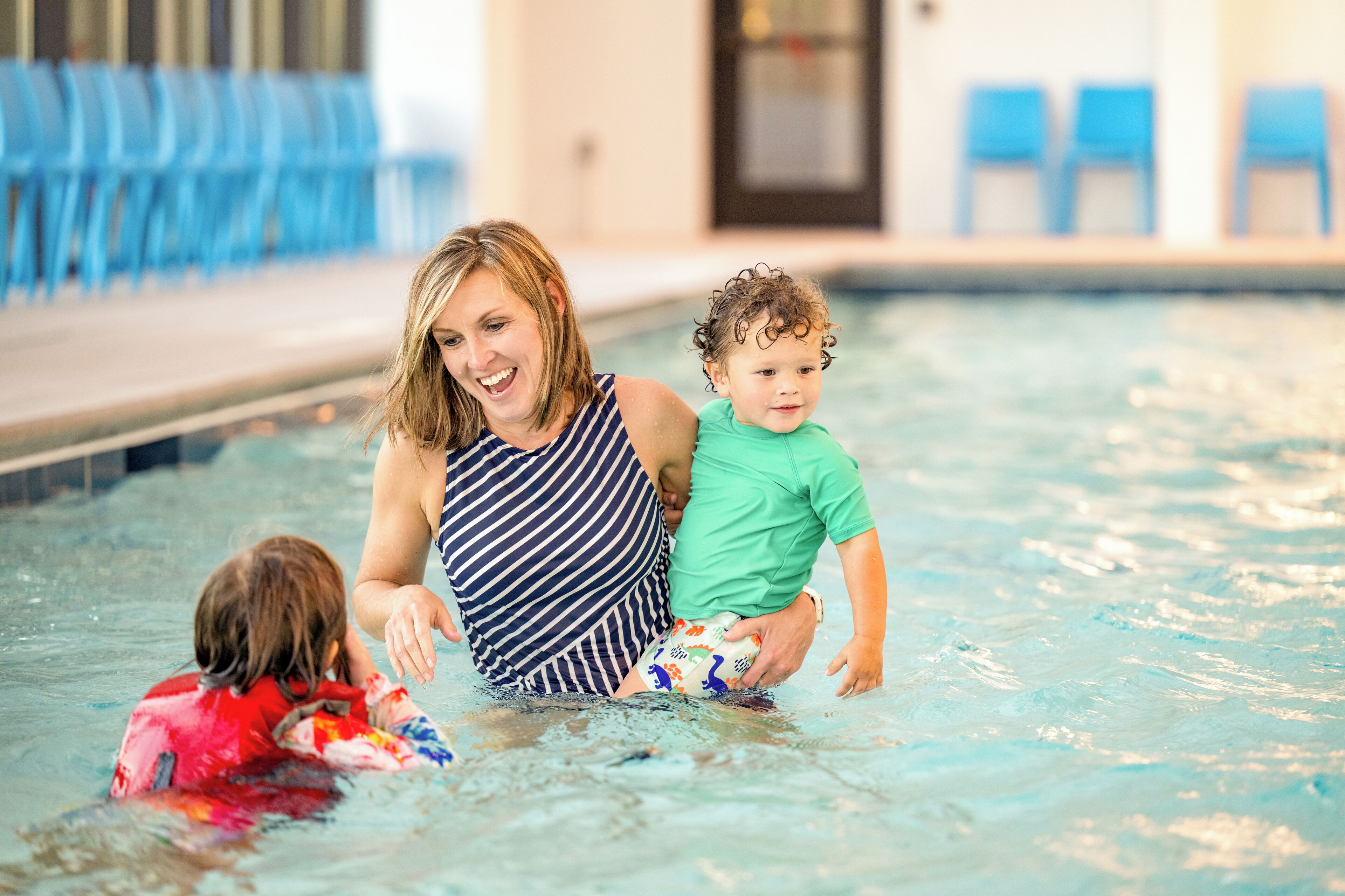 A swimming pool with blue chairs in the background.