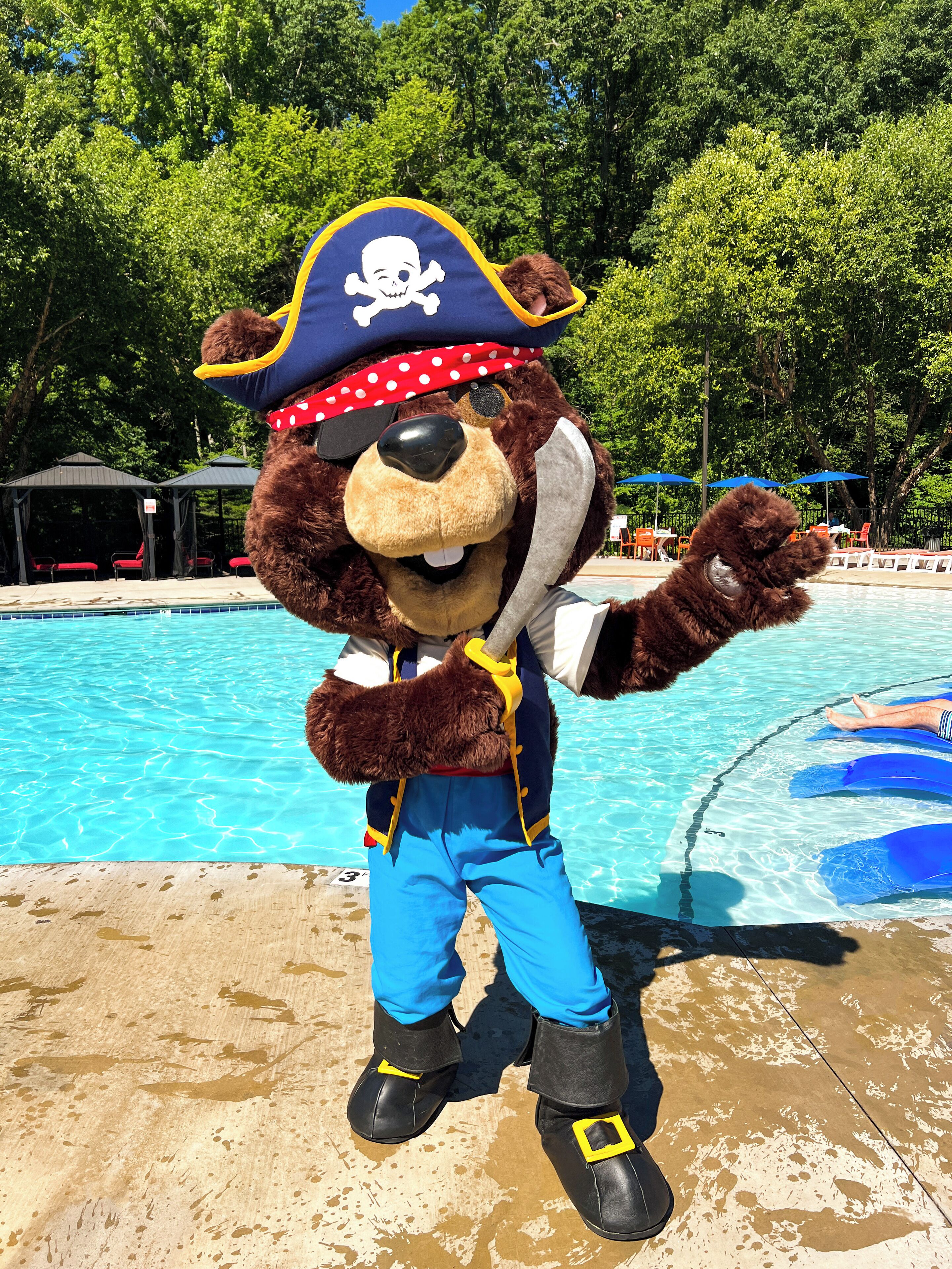 Un personaje con disfraz de pirata posa junto a una piscina.