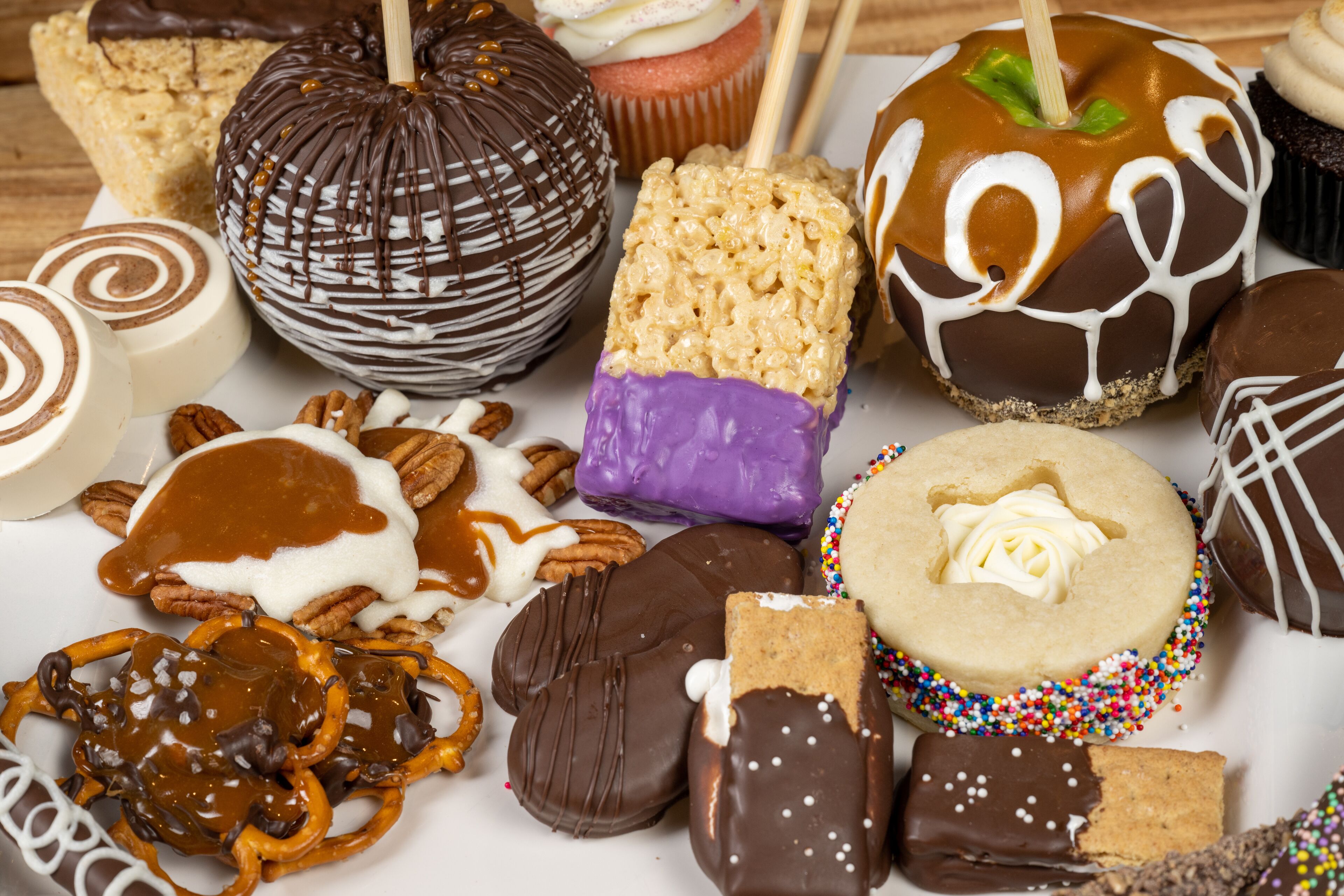 A variety of desserts including caramel apples, cupcakes, and cookies.