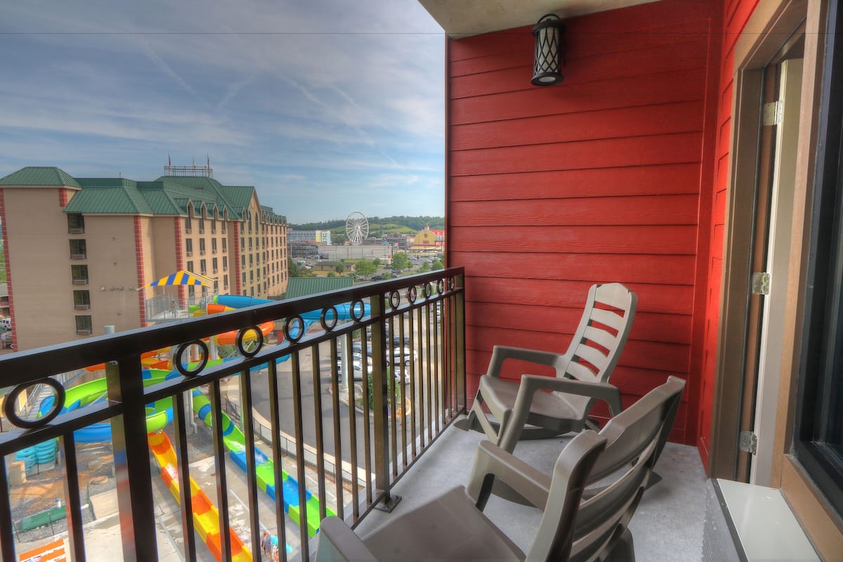 Un balcon avec vue sur un parc aquatique, comprenant un toboggan aquatique coloré et une grande roue.