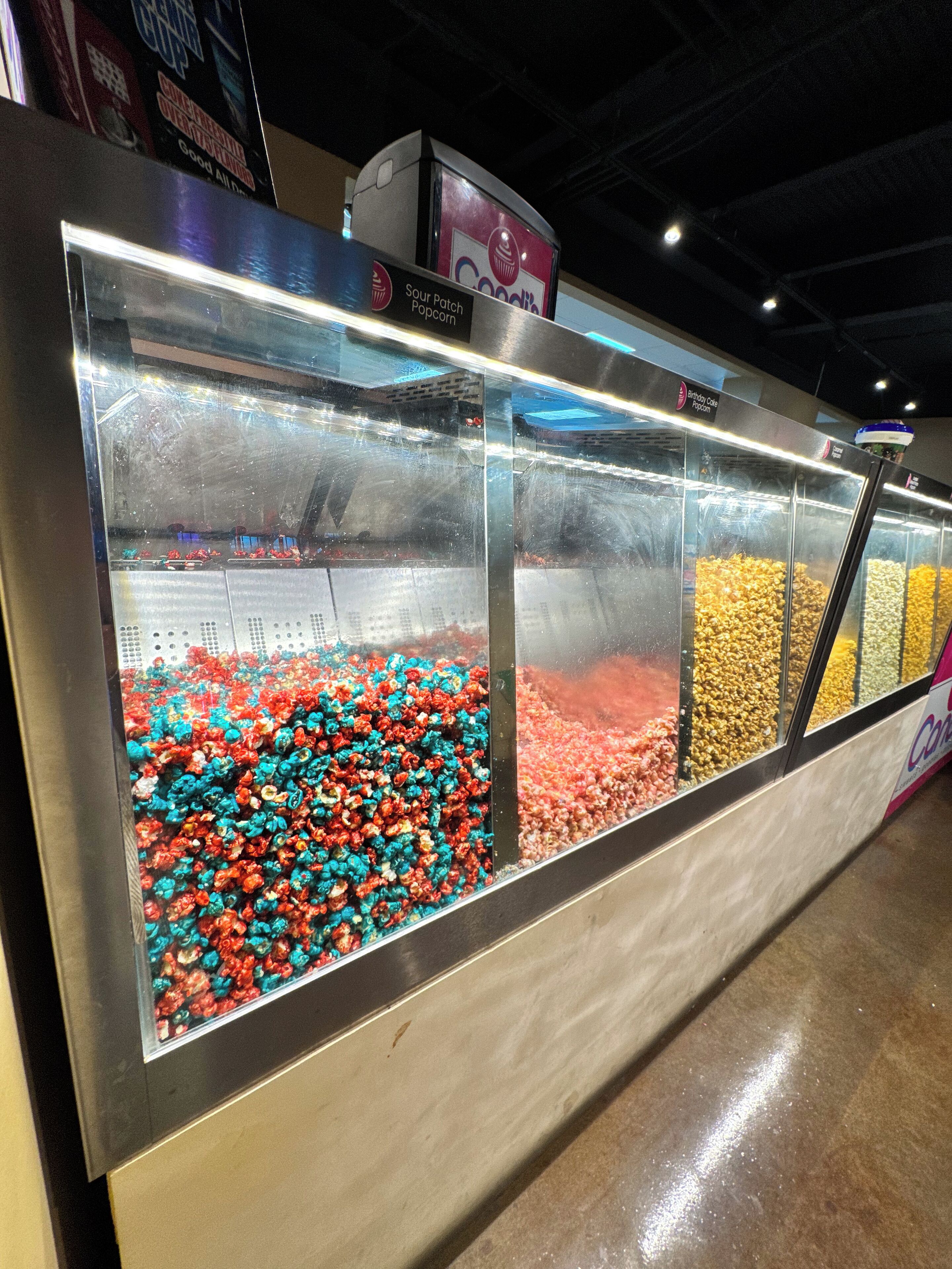 A candy display with various colors of popcorn and other snacks.